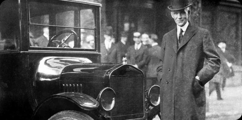 Henry Ford standing by a Ford.