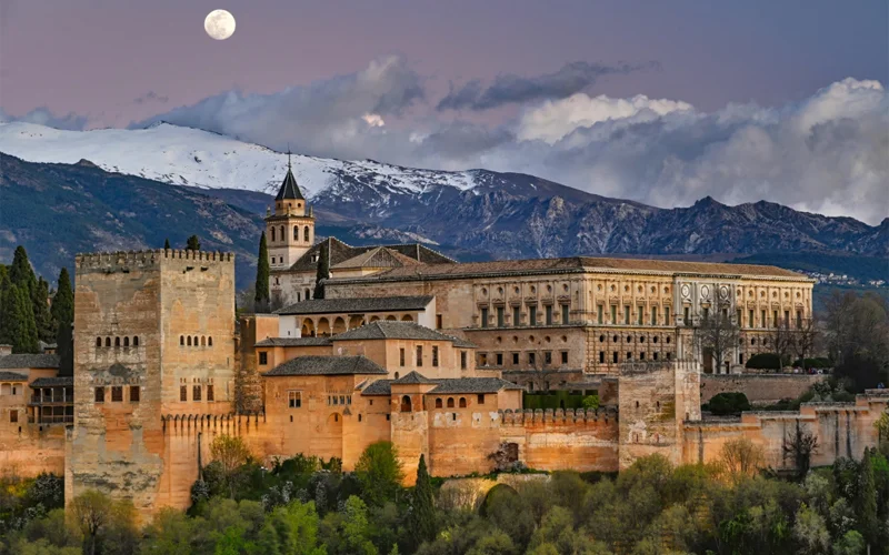 Crowning a Granada hill, the Alhambra embodies the architectural golden age of Muslim rule on the Iberian Peninsula. Its plain walls belie a refined interior. The 14th-century Comares Palace (with its tower at far left) was one of several built by a succession of sultans. A predominant palace (at right) was added later for a Christian king.