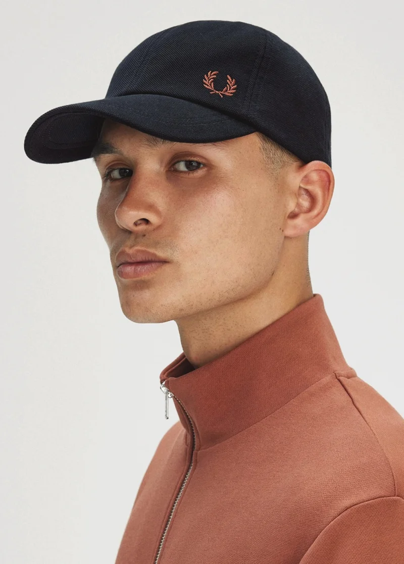 Male model wearing a Fred Perry Piqué Classic Cap in Navy / Cinnamon