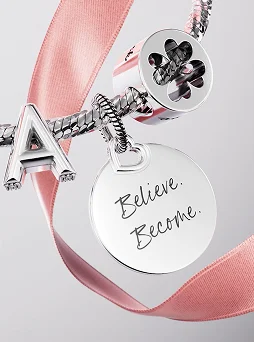 Charm bracelet stacked with letter, clover and engravable charms. Engravable charm says