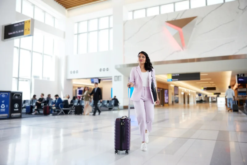 A woman rolls her suitcase through the airport.
