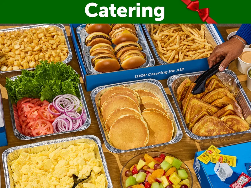 An assortment of IHOP Catering offerings, featuring tins of crispy potatoes, scrambled eggs, pancakes, and bacon