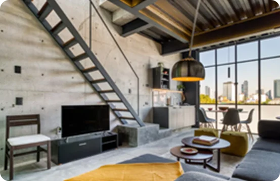 Modern loft with concrete walls, metal staircase, and large windows overlooking the city skyline.