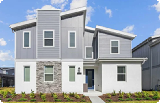 Modern two-story home with gray siding, white trim, and a stone accent under a bright blue sky.