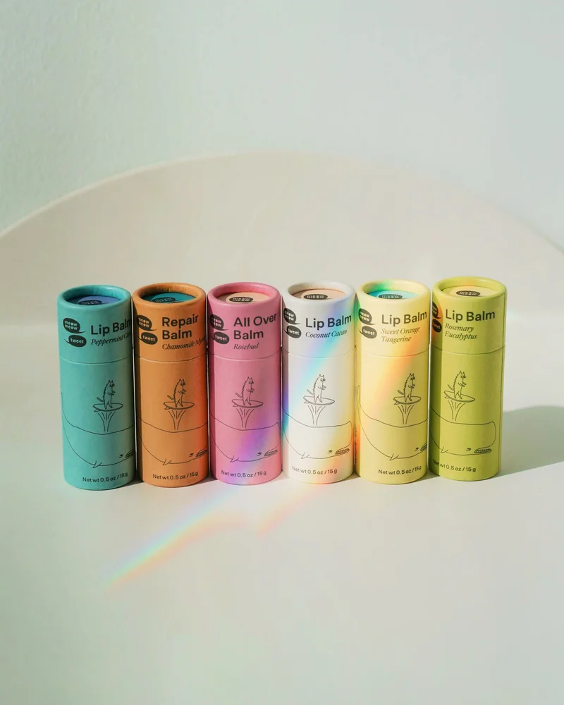 A line of rainbow-colored balms with a prism reflection over them