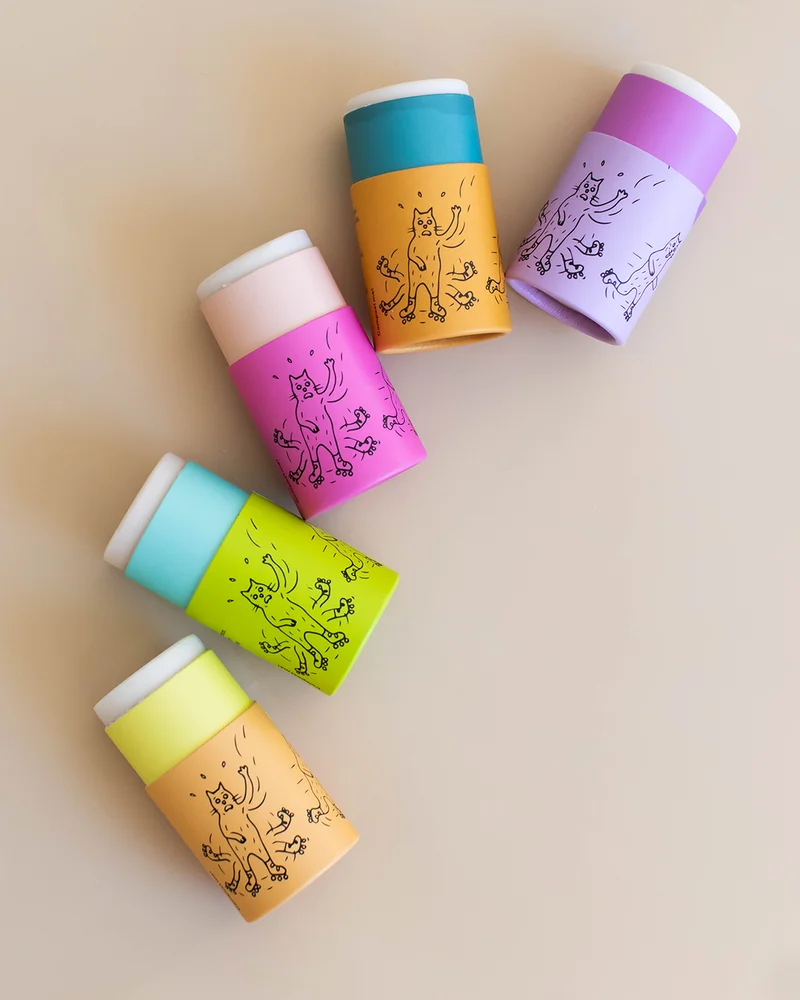 A rainbow of deodorant tubes on a tan background