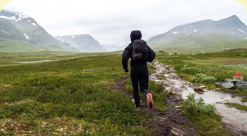 A person running on a dirt trail near mountains.