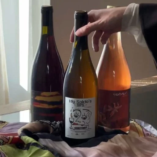 Hand reaching toward wine bottles