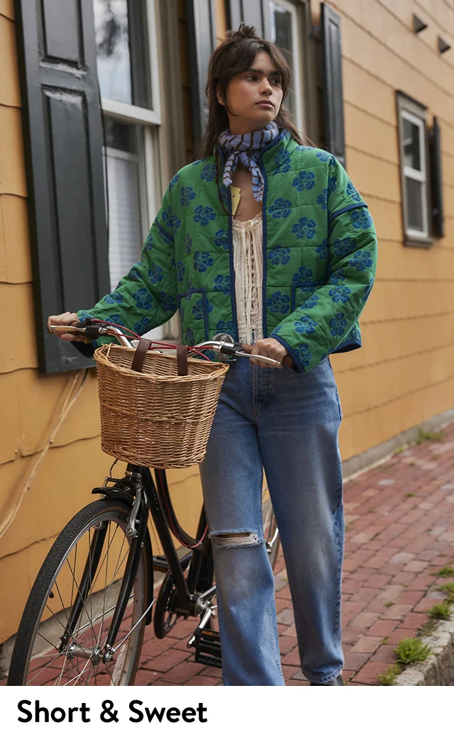 A woman wearing a green floral-print jacket with blue jeans.