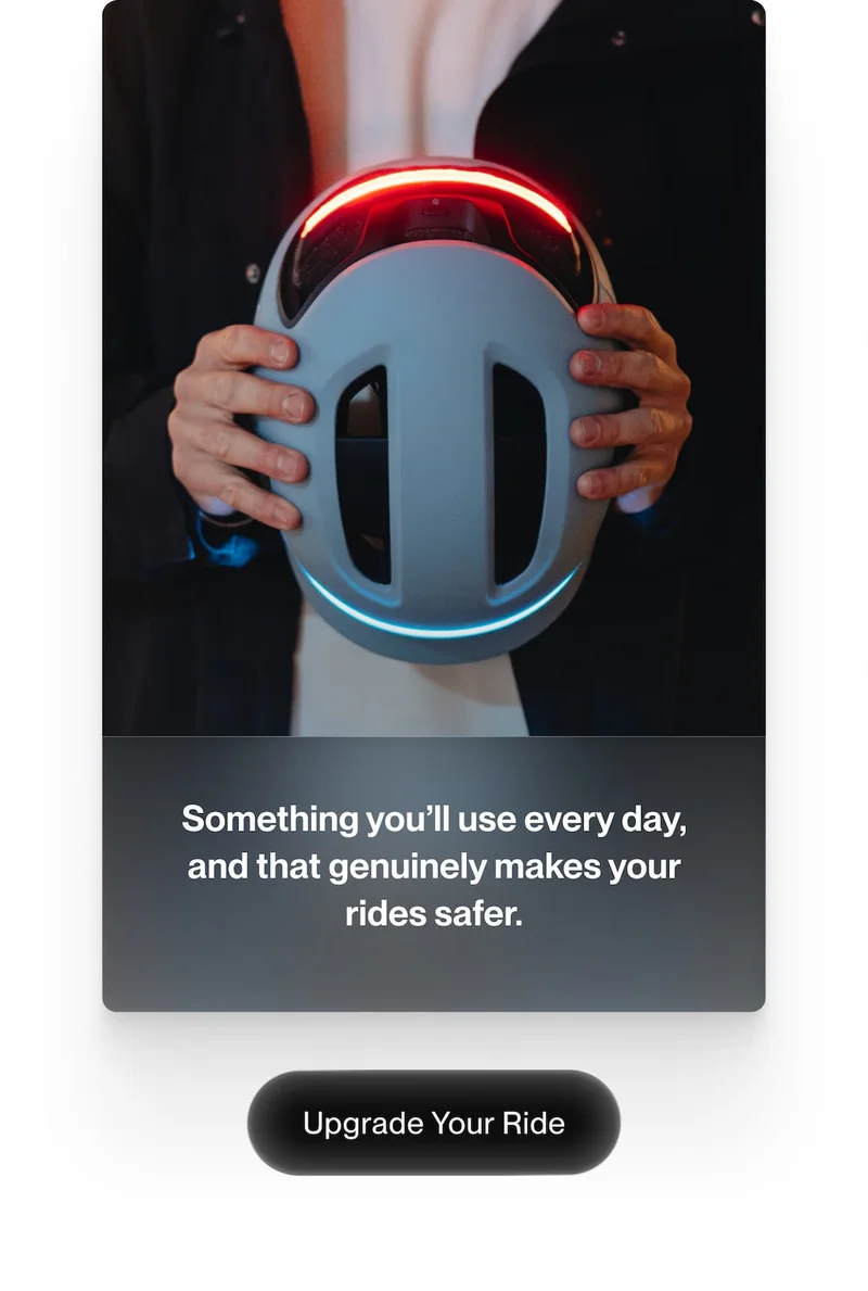 UNIT 1 smart bike helmet held from the back, showing integrated red rear light and blue front light, highlighting everyday safety features