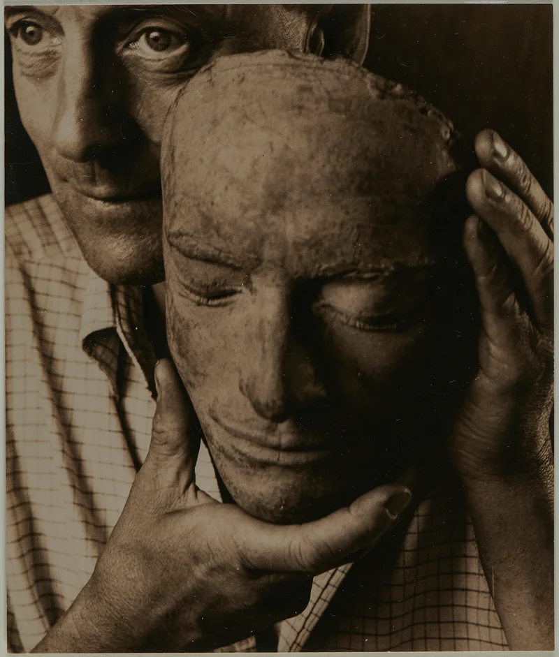 A man holds a mask beside his face