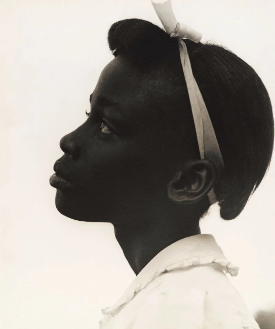 A girl in side profile with a ribbon in her hair