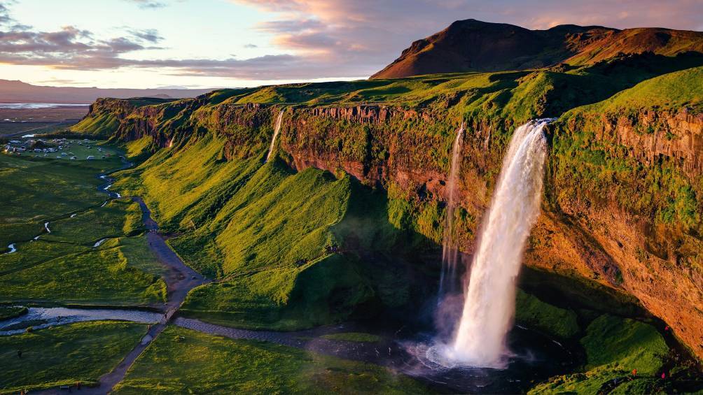Image description: Aerial of Seljalandsfoss waterfall during the Midnight Sun in Iceland.
