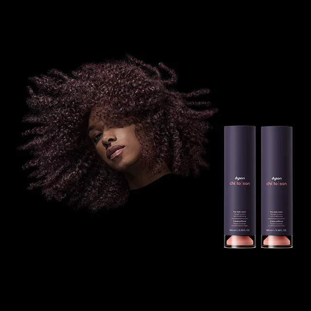 Model with curly hair next to the Dyson Chitosan styling Pre-style cream and Post-style serum