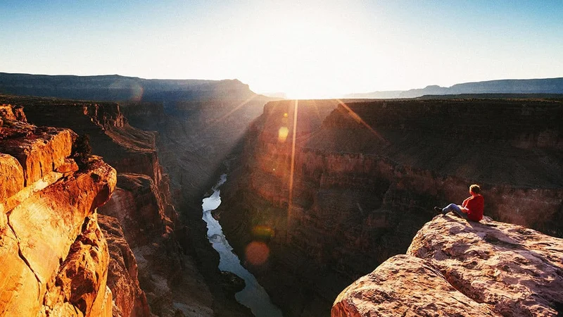 Image description: Man watching sunrise over Grand Canyon National Park