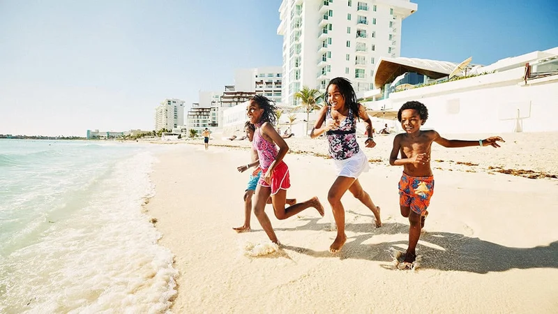 Image description: Four kids running on the beach in Cancun