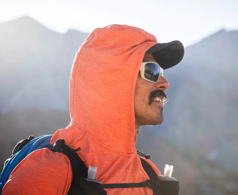 A trail runner wearing a hydration vest looks into the distance.