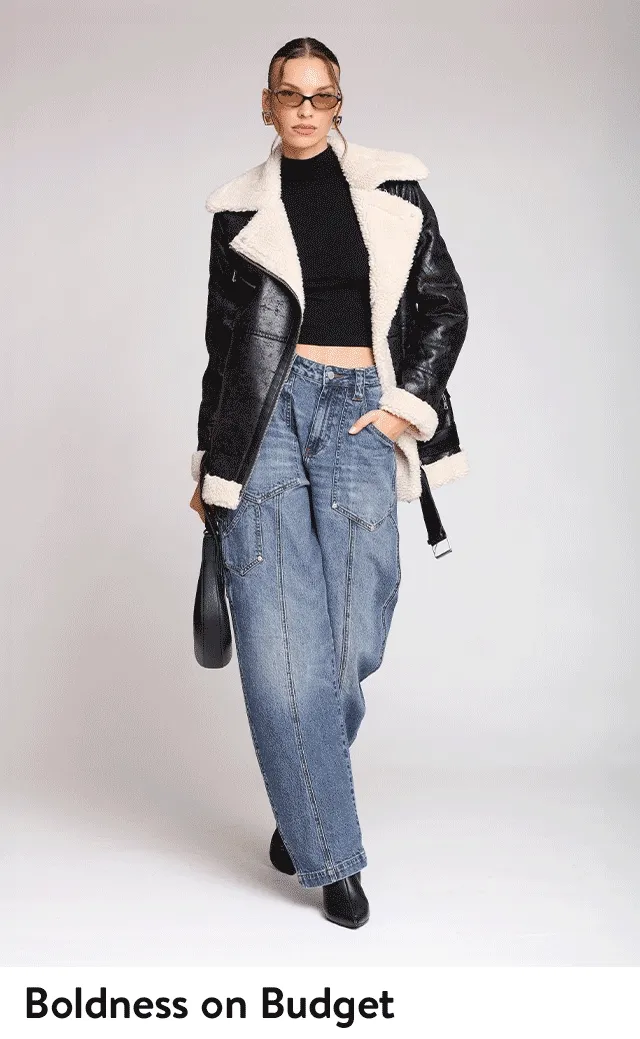 A woman wearing a faux-leather biking jacket with faux-shearling trim and jeans.