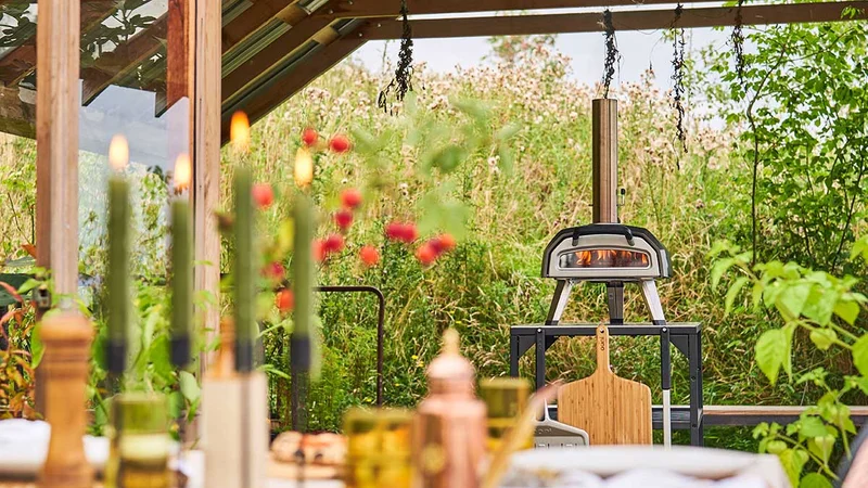 Ooni Karu 2 on and Ooni Table surrounded by an outdoor dinner set with candles and flowers