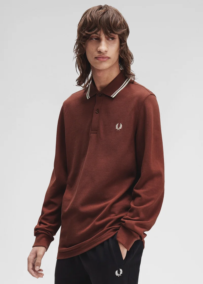 Male model with wolf cut wears a long sleeved Fred Perry shirt