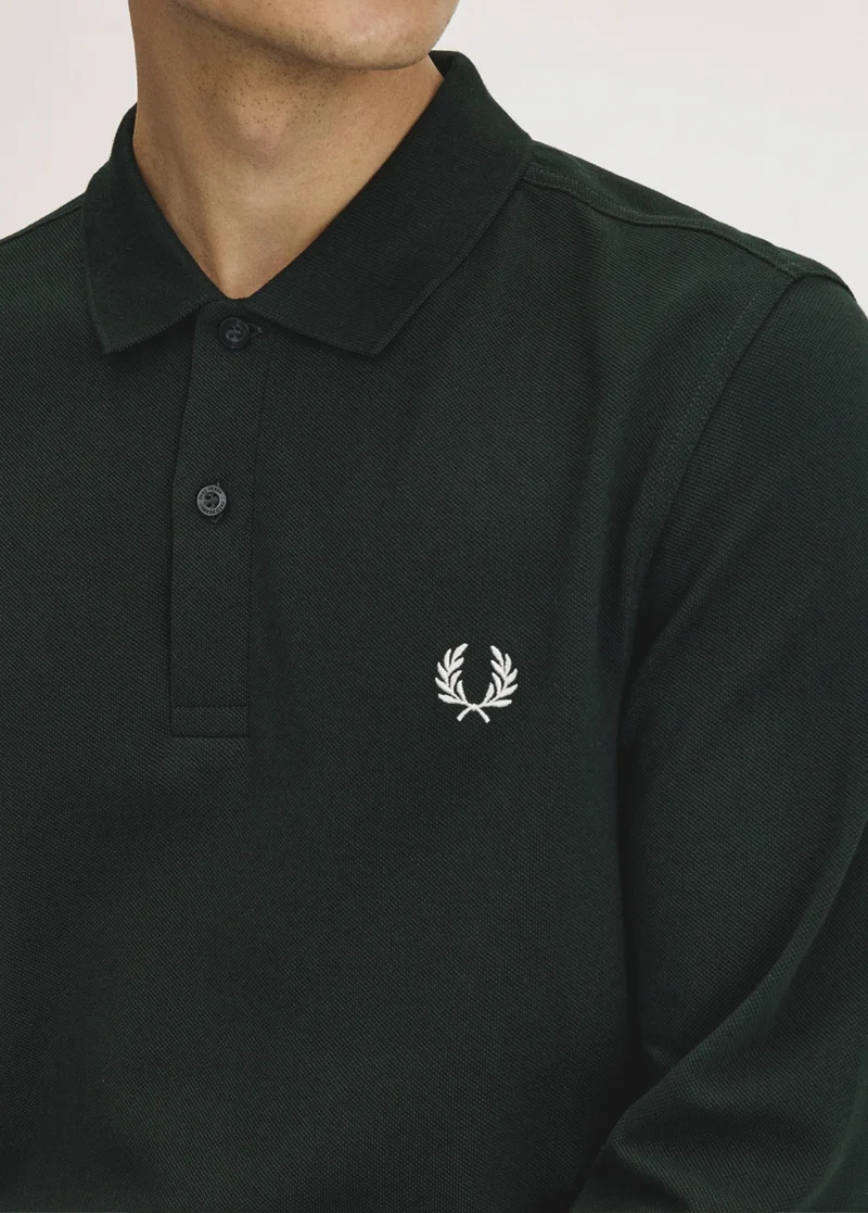 A male model wearing a solid colour long sleeved Fred Perry Shirt in Night Green