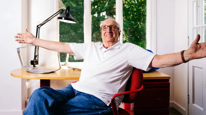 Bruce Hannah sits with arms outstretched in Morrison Hannah chair in a home office.