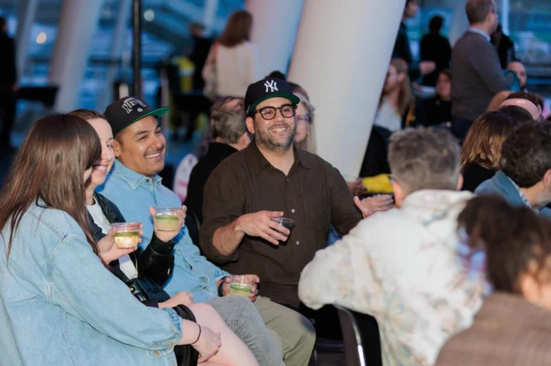 A group of people sitting together holding cups and smiling