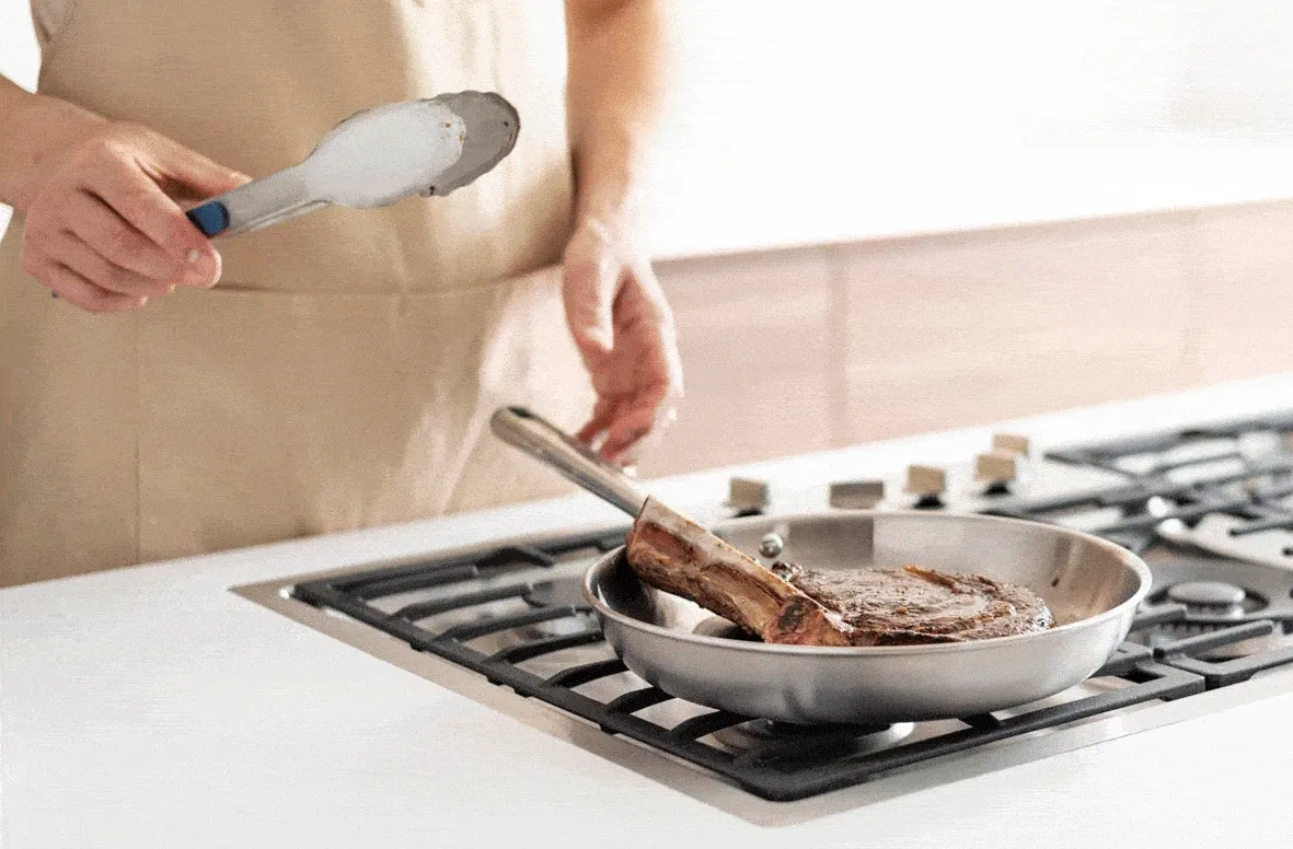 Cooking steak with tongs