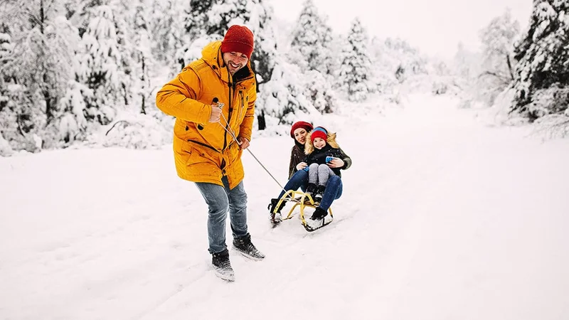 Image description: Family sledding in the snow