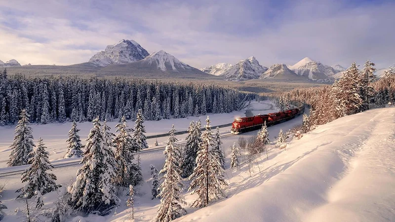 Image description: Train passes through Morant's Curve in Banff National Park in the winter