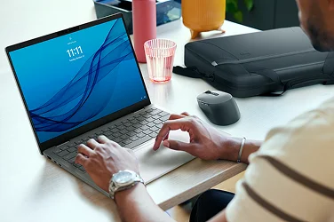 Over-shoulder view of a person working on a Dell 14 Plus AI laptop computer in an office setting.