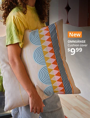 Person holding the new OMMJÄNGE multicolor cushion cover.