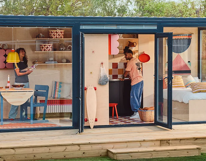 Two people standing in a modern tiny house decorated with the IKEA OMMJÄNGE collection.