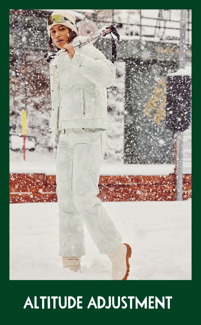A woman wearing a white coat and matching ski pants.