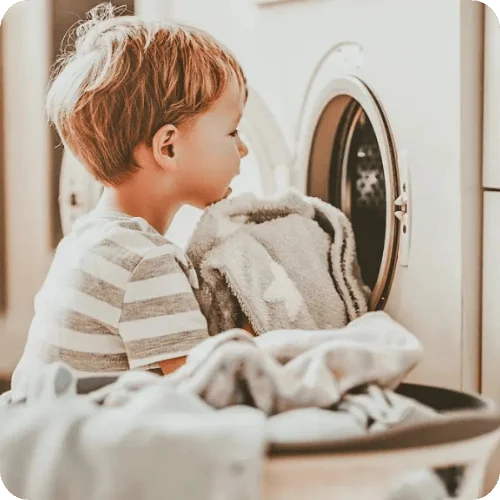 a toddler loading laundry into the machine, a basic life skill