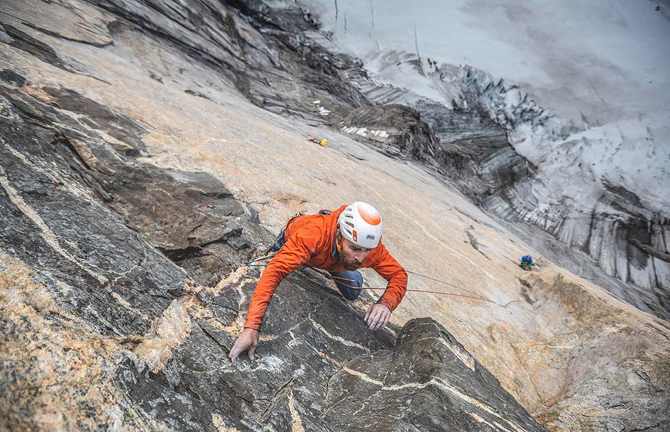 Photo of a climber in an orange jacket high on a big wall.