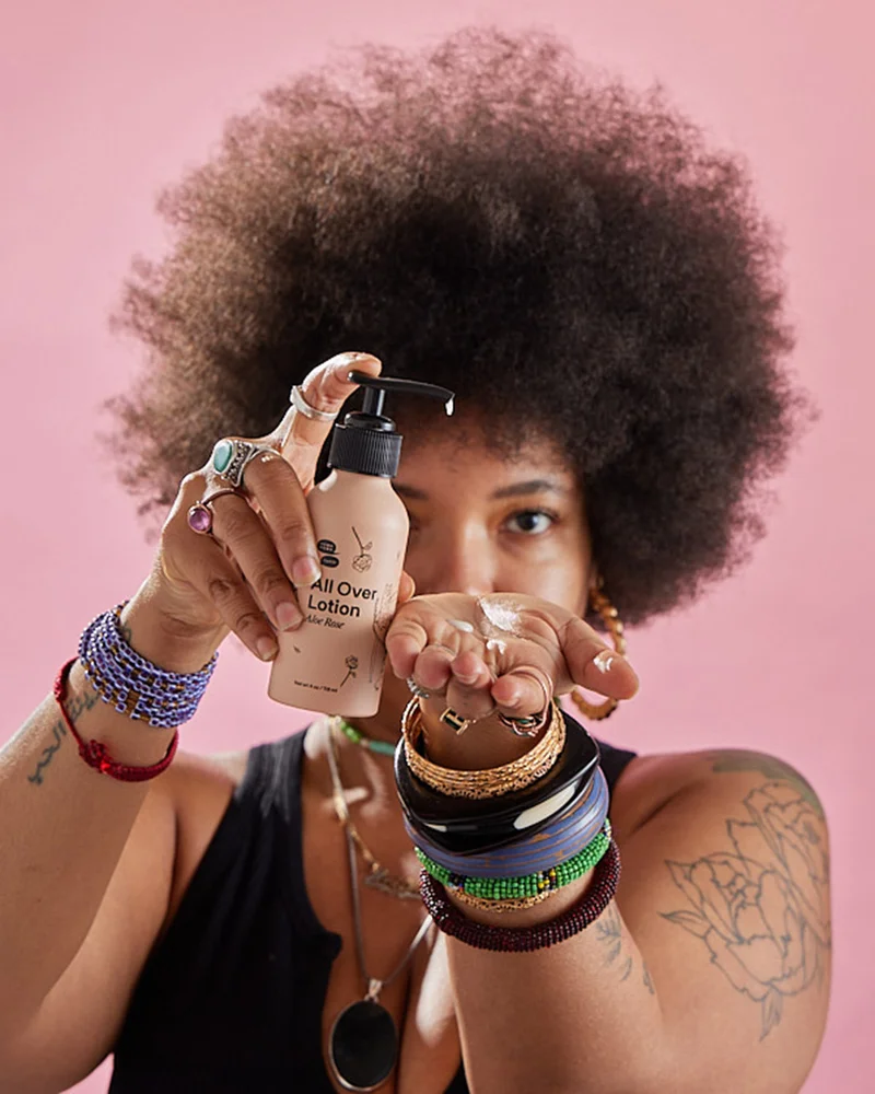 A Black woman with an Afro pumping lotion into her hand