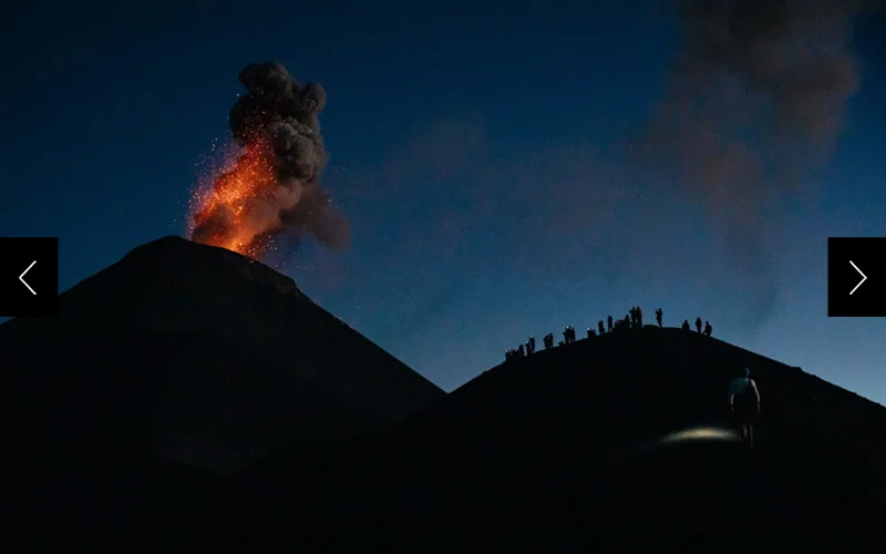 Hikers (right) are pictured getting a close-up view of the erupting Volcán de Fuego in Guatemala (left) at night.