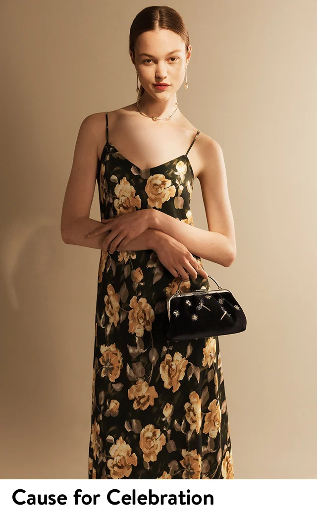 A woman wearing a floral slipdress with a velvet handbag.