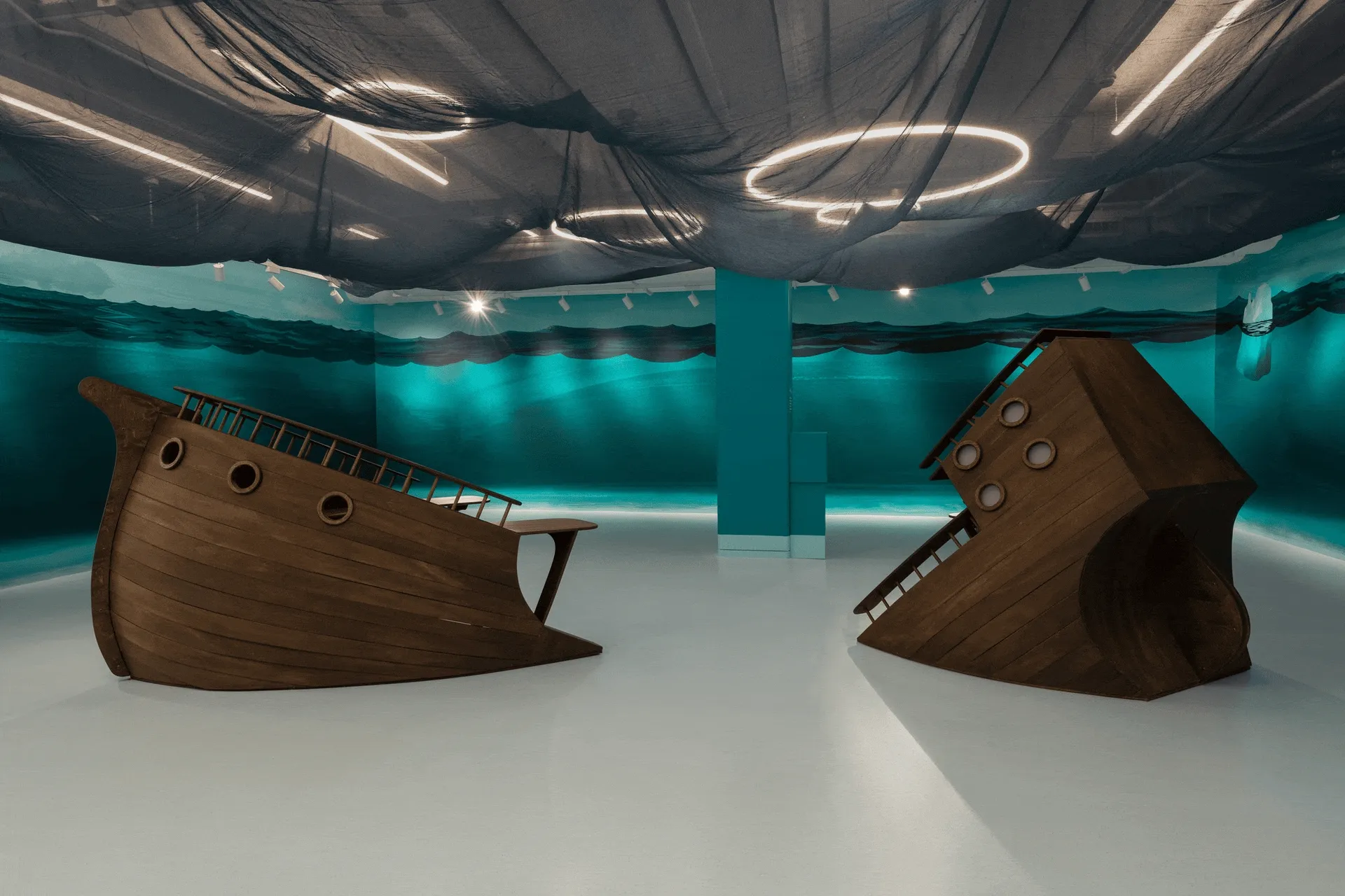 A GIF featuring two images of a blue room with a ship installation, one showing bare walls and one showing walls decorated with painted fish