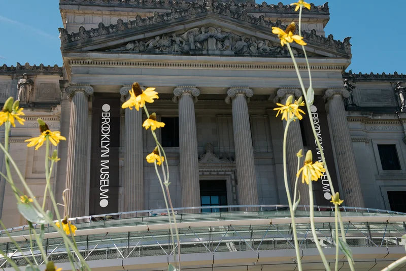 The Brooklyn Museum exterior surrounded by yellow flowers