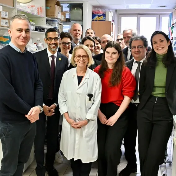 A photo of a group of smiling people standing in a crowded laboratory to celebrate the partnership.