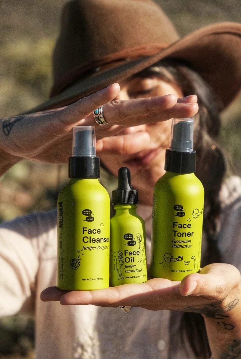 A tan skinned person holds three lime green bottles up for the camera