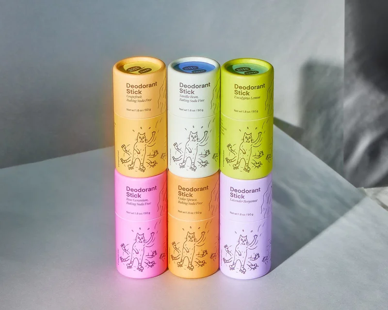 Six multicolor deodorant sticks are stacked on a gray background