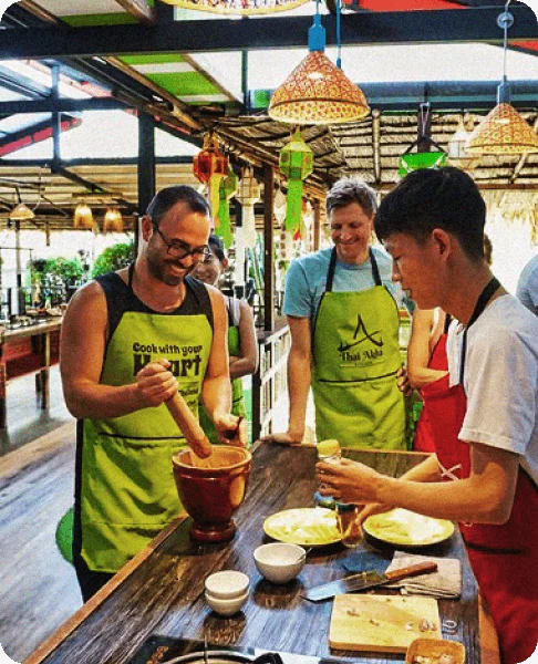 Image Description: A traveler pounding chili with a pestle and mortar during a cooking class in Thailand