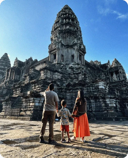Image Description: A family of three admiring a massive sandstone tower at Angkor Wat near Siem Reap, Cambodia