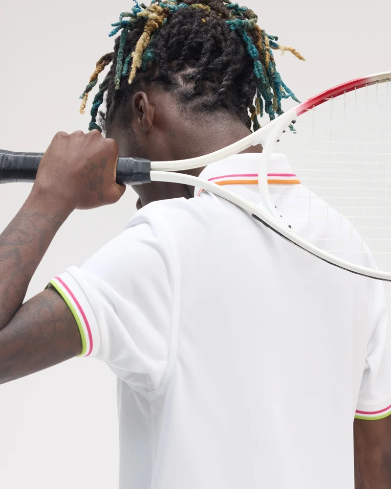 Man wearing The White Fred Perry Tennis Shirt holding a tennis racket