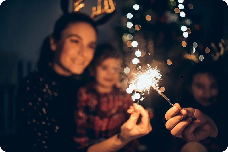 People holding a sparkler at night.