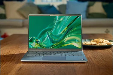 A front view of an open laptop with a green screensaver sitting on a table.