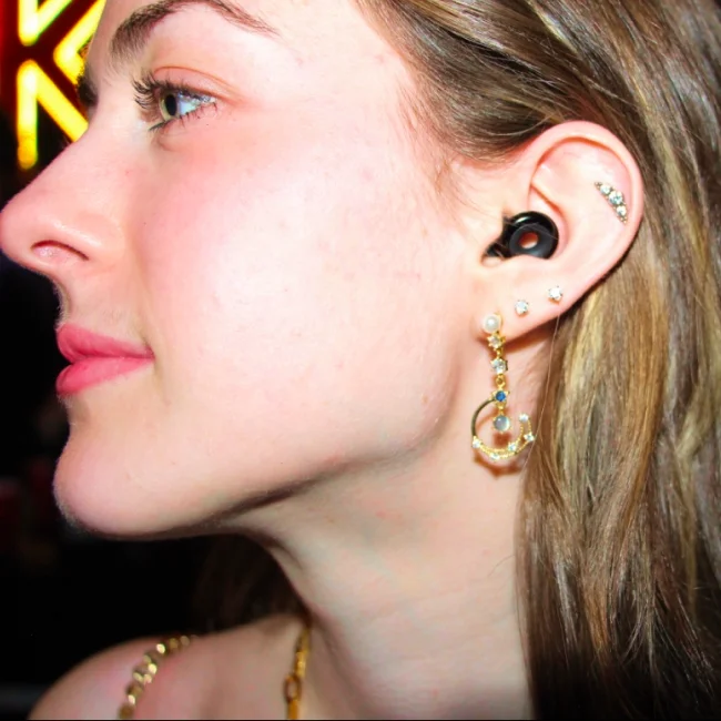 Side profile of a woman wearing Loops alongside multiple ear piercings.